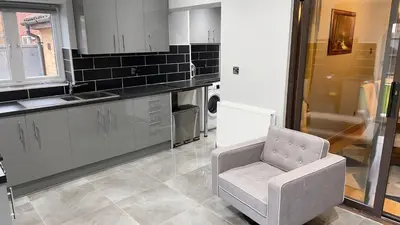a kitchen with a chair and a sink at Cosy 4 bedroom holiday let Stevenage 22mins from London on the train in Stevenage