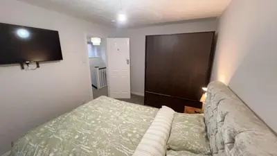 a bedroom with a couch and a television on the wall at Cosy 4 bedroom holiday let Stevenage 22mins from London on the train in Stevenage