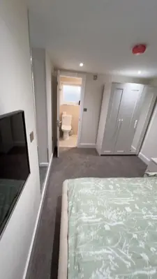 a bedroom with a bed and a tv and a bathroom at Cosy 4 bedroom holiday let Stevenage 22mins from London on the train in Stevenage