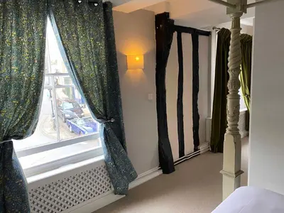 a bedroom with a window with curtains on it at The Bull Inn in Woodbridge