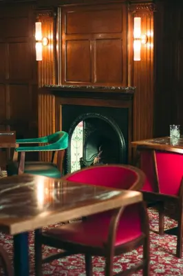 a room with a fireplace and tables and chairs at The Bull Inn in Woodbridge