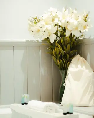 a vase filled with white flowers on top of a sink at The Bull Inn in Woodbridge