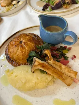 a plate of food with a pie and a cup of gravy at The Bull Inn in Woodbridge
