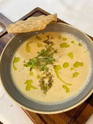 a bowl of soup with a piece of bread and parsley at The Bull Inn in Woodbridge