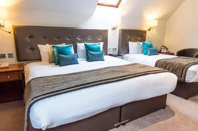 two beds in a hotel room with blue pillows at Ufford Park Resort in Woodbridge