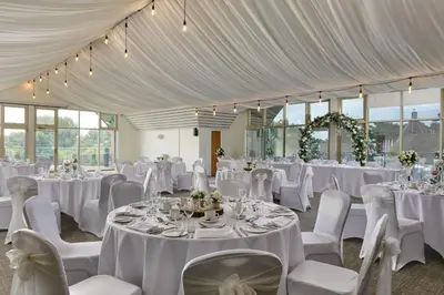 a room filled with tables and chairs with white linens at Ufford Park Resort in Woodbridge