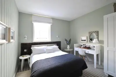 a bedroom with a bed and a desk and a window at The Crown Hotel in Woodbridge