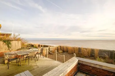 a deck with a table and chairs overlooking the ocean at Coastguards in Aldeburgh