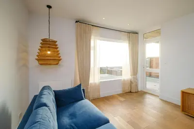 a blue couch in a living room with a window at Coastguards in Aldeburgh