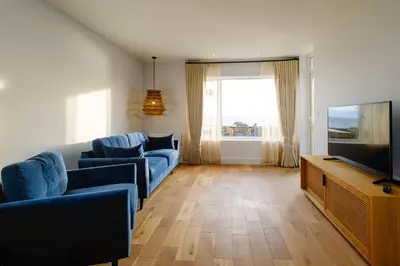 a living room with blue couches and a flat screen tv at Coastguards in Aldeburgh