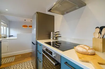 a kitchen with a stainless steel stove and blue cabinets at Coastguards in Aldeburgh