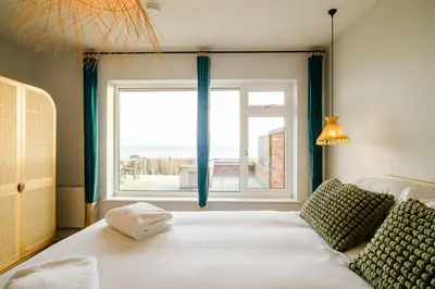 a bedroom with a bed and a large window at Coastguards in Aldeburgh