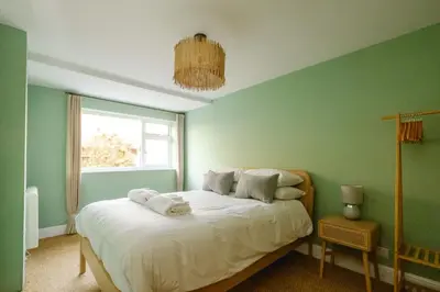a bedroom with a bed with white sheets and a window at Coastguards in Aldeburgh
