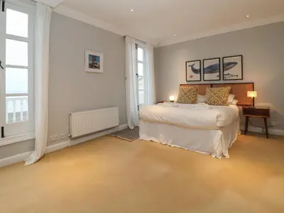 a bedroom with a large bed and two windows at 42 Crag Path in Aldeburgh
