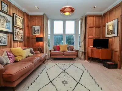 a living room with a leather couch and a television at 42 Crag Path in Aldeburgh