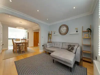 a living room with a couch and a clock on the wall at Pass the Keys Centrally located modern and spacious 3 Bed terrace in Cambridge