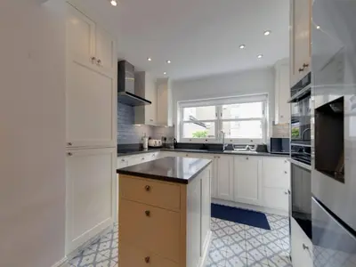 a large kitchen with white cabinets and a window at Pass the Keys Centrally located modern and spacious 3 Bed terrace in Cambridge