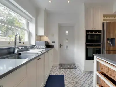 a kitchen with white cabinets and a sink and a window at Pass the Keys Centrally located modern and spacious 3 Bed terrace in Cambridge