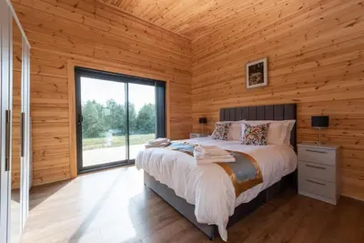 a bedroom with a bed and a large window at Meadow Valley Lodge 3 - Hot Tub in Hintlesham