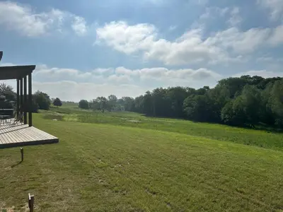 a large green field with a gazebo in the foreground at Meadow Valley Lodge 3 - Hot Tub in Hintlesham