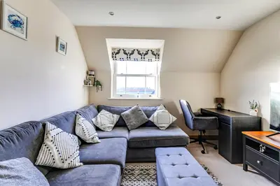 a living room with a blue couch and a window at Entire 2 Bed Flat Contractors Families and Relocators in Ware