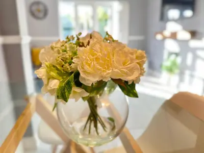 a glass vase filled with yellow flowers on a table at Modern 3 bed House with two bathrooms! Free parking! in Bar Hill