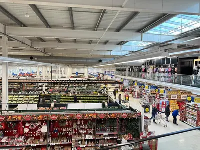a large supermarket aisle with people walking through a store at Modern 3 bed House with two bathrooms! Free parking! in Bar Hill