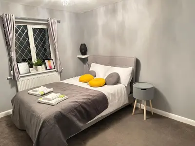 a bedroom with a bed with yellow pillows and a window at Modern 3 bed House with two bathrooms! Free parking! in Bar Hill