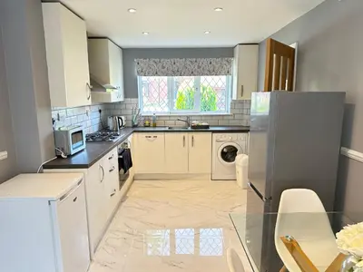 a kitchen with white appliances and a window at Modern 3 bed House with two bathrooms! Free parking! in Bar Hill