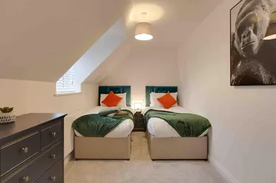 a attic bedroom with two beds and a dresser at Kestrel Gardens Dunmow in Great Dunmow