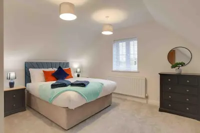 a bedroom with a bed and a window and a dresser at Kestrel Gardens Dunmow in Great Dunmow