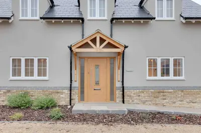 a house with a wooden door in front of it at Kestrel Gardens Dunmow in Great Dunmow