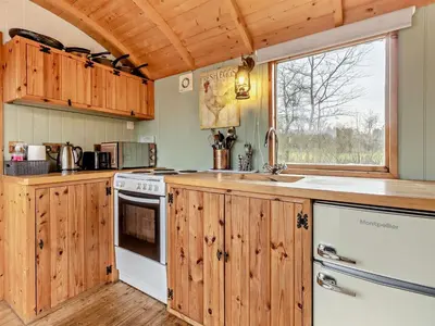 a kitchen with wooden cabinets and a large window at 1 Bed in Norwich oc-57900 in East Harling