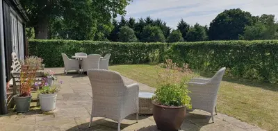 a patio with chairs and a table and some plants at The Granary Stradbroke in Fressingfield