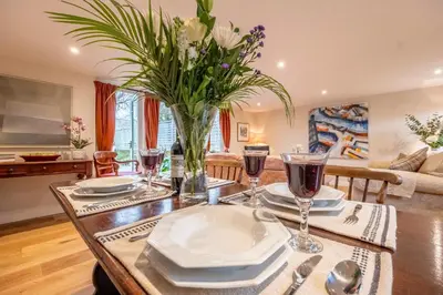 a dining table with a vase of flowers on it at Dedham Vale Cottage with Swimming Pool mid May to mid Sep - Yew Tree Barn in Higham