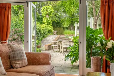 a living room with a couch and a sliding glass door at Dedham Vale Cottage with Swimming Pool mid May to mid Sep - Yew Tree Barn in Higham