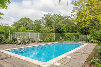 a swimming pool in a yard with chairs and tables at Dedham Vale Cottage with Swimming Pool mid May to mid Sep - Yew Tree Barn in Higham
