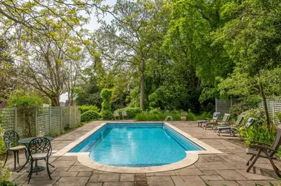 a swimming pool in a yard with chairs around it at Dedham Vale Cottage with Swimming Pool mid May to mid Sep - Yew Tree Barn in Higham