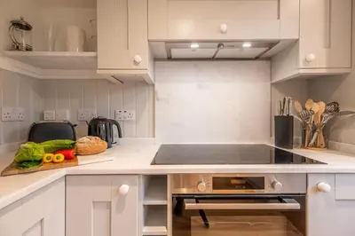 a kitchen with white cabinets and a sink at Dedham Vale Cottage with Swimming Pool mid May to mid Sep - Yew Tree Barn in Higham