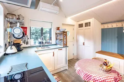 a kitchen with white cabinets and a blue counter top at The Little House, Orford in Woodbridge