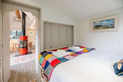a bedroom with a bed with a colorful blanket at The Little House, Orford in Woodbridge
