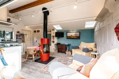 a living room with a stove in the middle at The Little House, Orford in Woodbridge