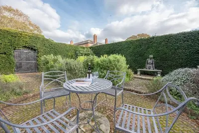 a patio with four chairs and a table in a garden at The Little House, Orford in Woodbridge