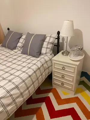 a bedroom with a bed and a nightstand with a lamp at Jmk home in Lexden