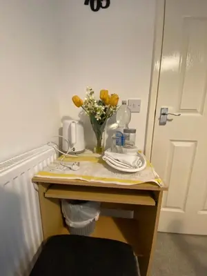 a table with a vase of yellow flowers on it at Jmk home in Lexden
