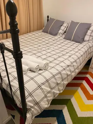 a bed with a black and white comforter and pillows at Jmk home in Lexden