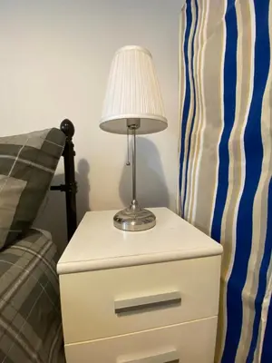a lamp on a night stand next to a bed at Jmk home in Lexden