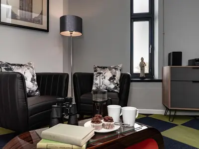 a living room with two chairs and a table with cupcakes at 9 Bed in Ipswich oc-62352 in Freston