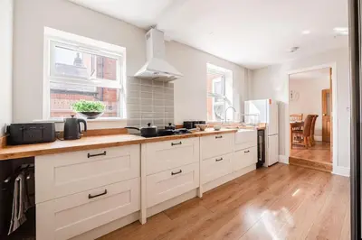a kitchen with white cabinets and a wooden floor at Host & Stay - Sherrington Road Abode in Ipswich