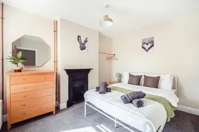 a bedroom with a bed and a dresser and a fireplace at Host & Stay - Sherrington Road Abode in Ipswich